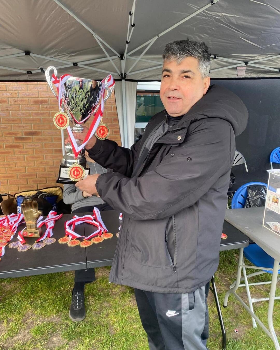 Organiser holding the first-place trophy beside a table of medals