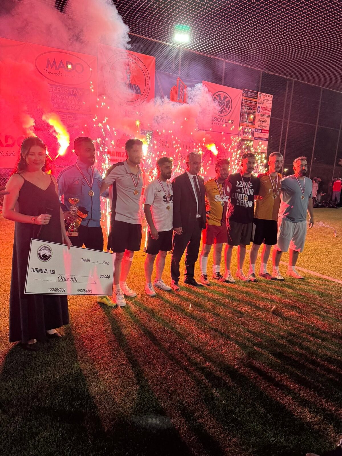 Tournament champions celebrating with the trophy, medals and winners' cheque amid fireworks